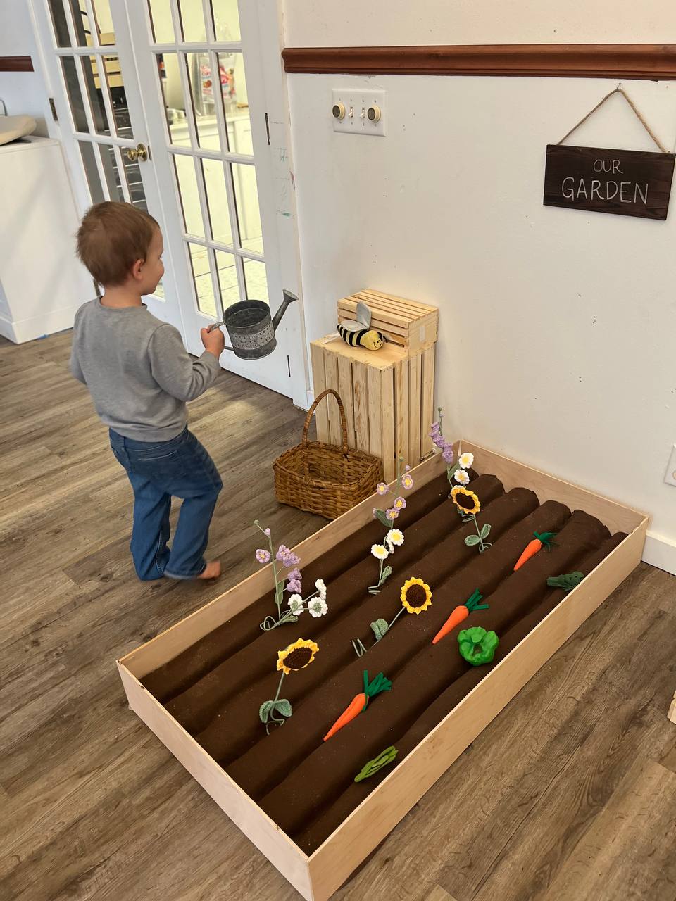 Toddler playing in the garden storefront at Storybook Settlement